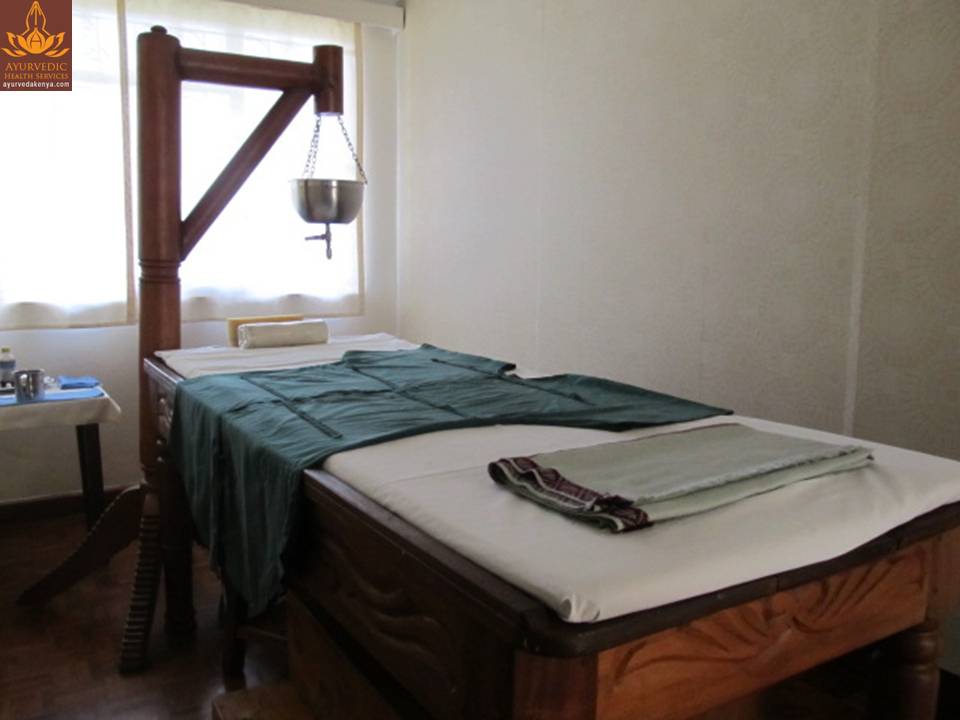 A treatment room with a traditional wooden Ayurvedic table